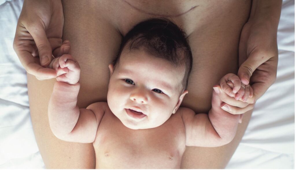 naked baby lying against naked mom c-section