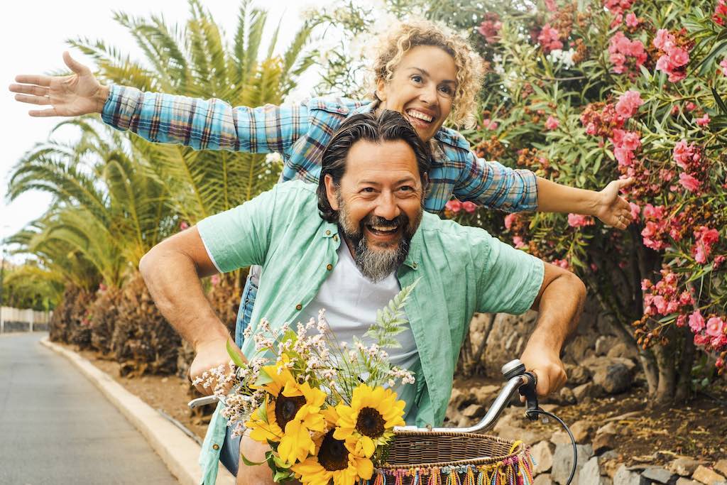 Active and smiling middle aged couple sharing one bike