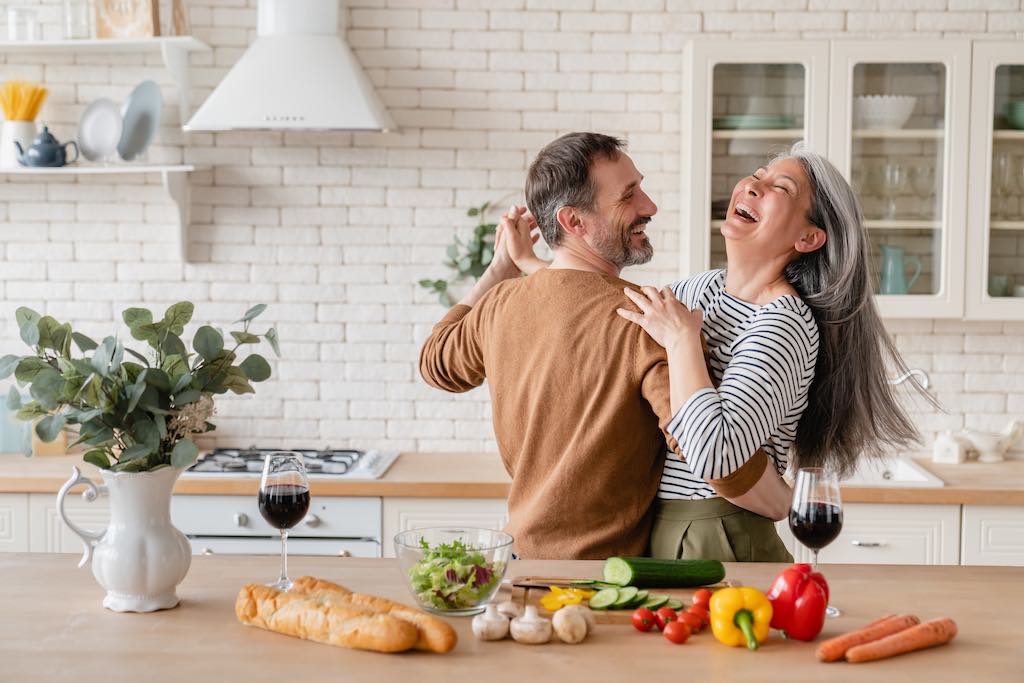 happy healthy lifestyle couple dancing in kitchen cooking healthy meal