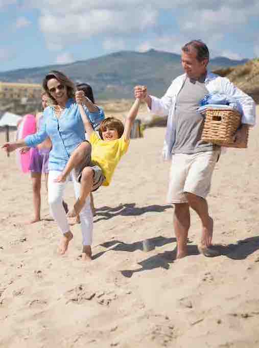 middle age couple holding young boy's hand on beach