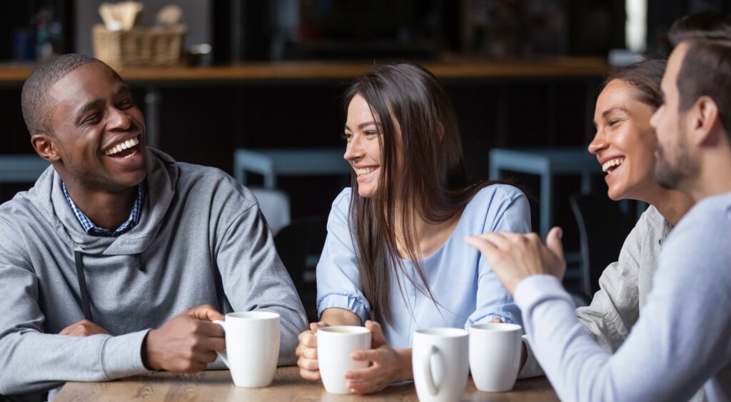 4 multicultural adults enjoying conversation at a cafe